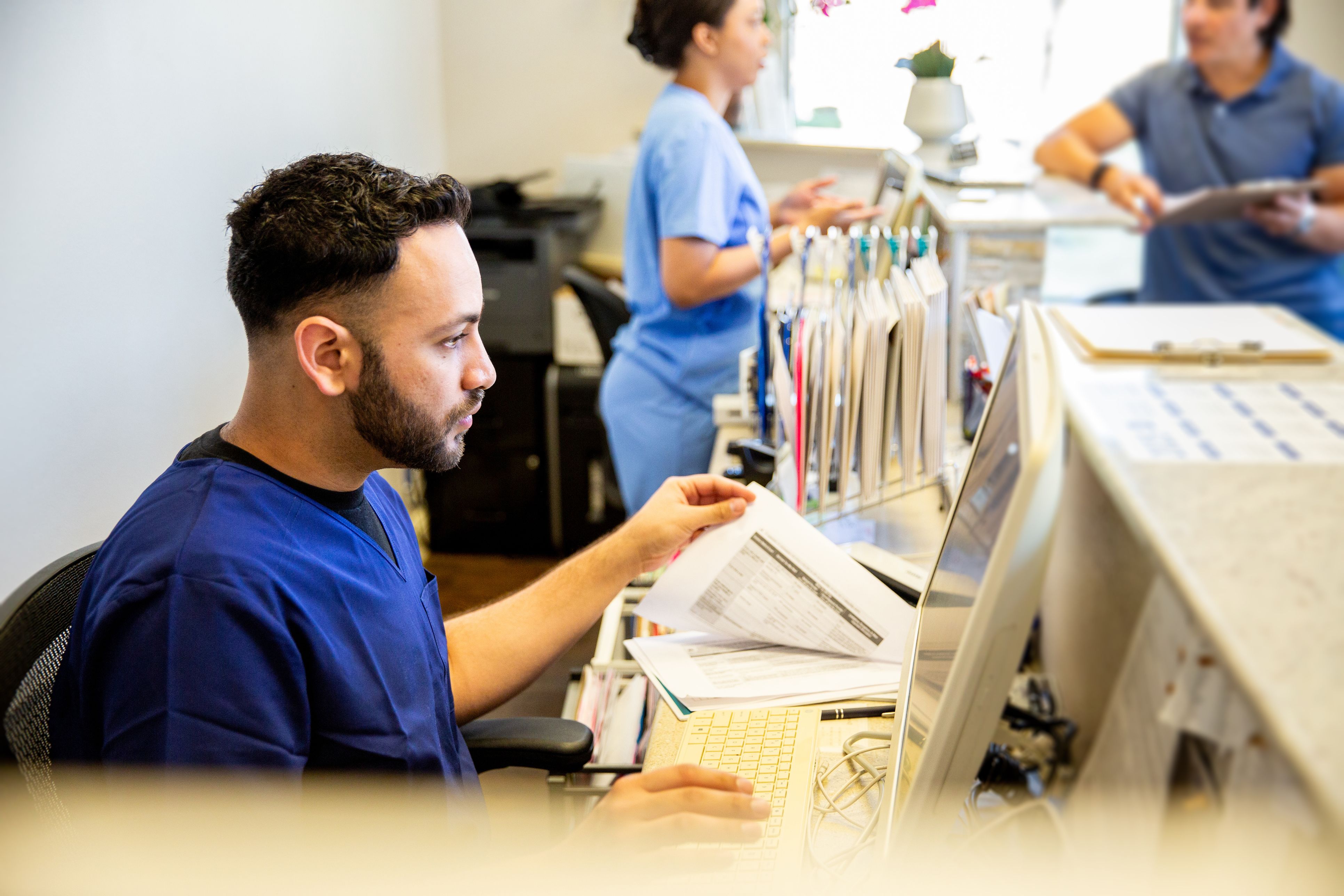 A health professional flips through paperwork at a desk.